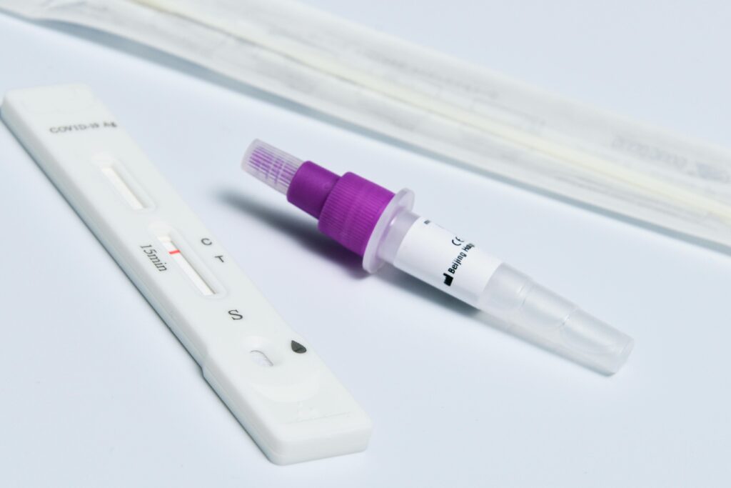 Close-up of a COVID-19 rapid antigen test kit featuring a swab, dropper, and test strip on a white surface.