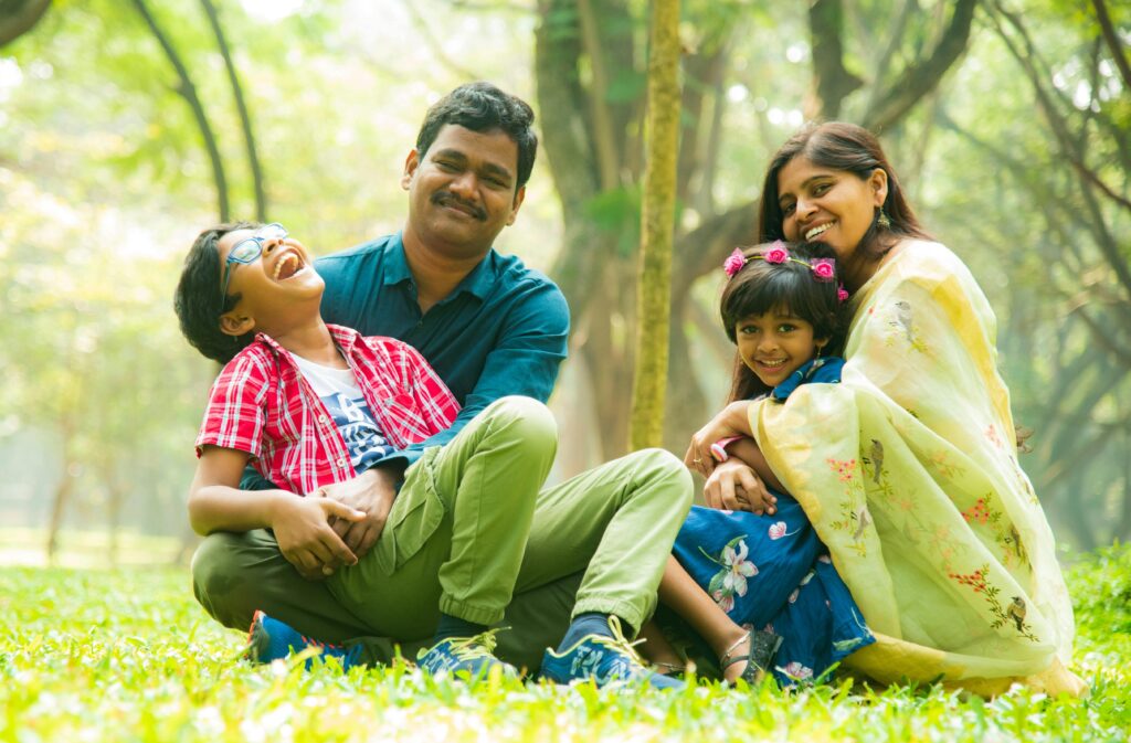 Cheerful family sitting on the grass, enjoying time outdoors together in a serene park.